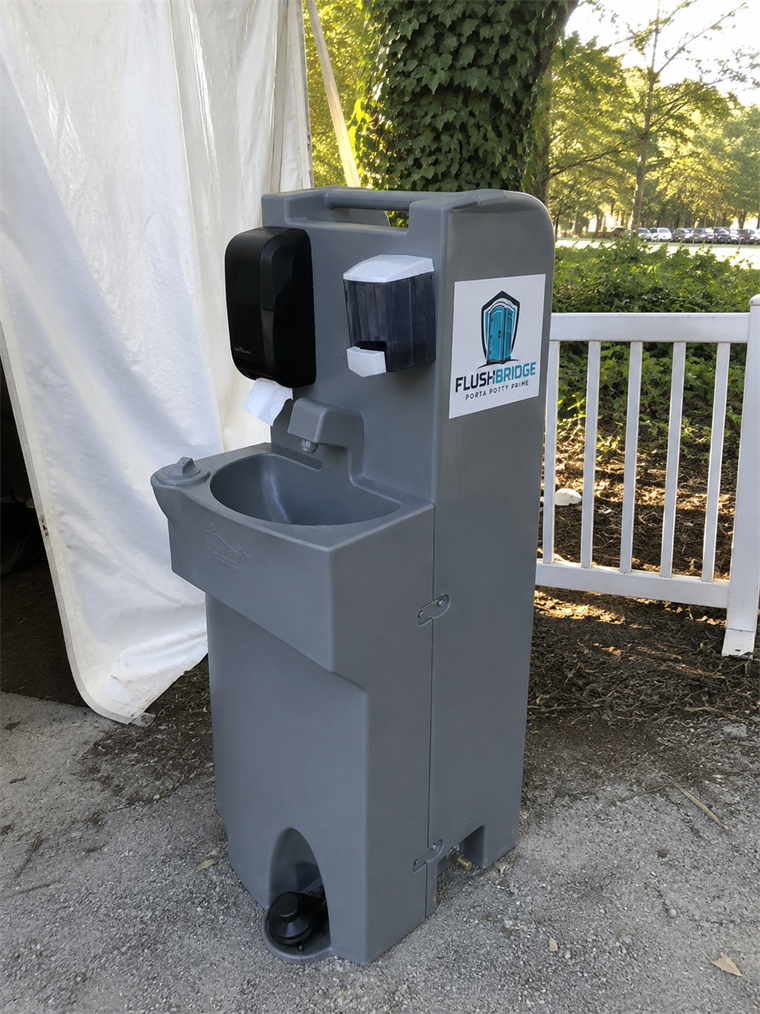 Portable handwashing station standing beside a white event marquee