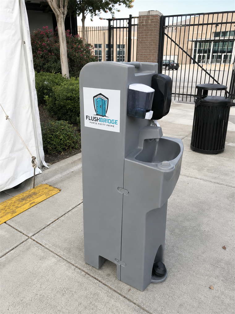 Portable handwashing station standing on paving beside an event marquee